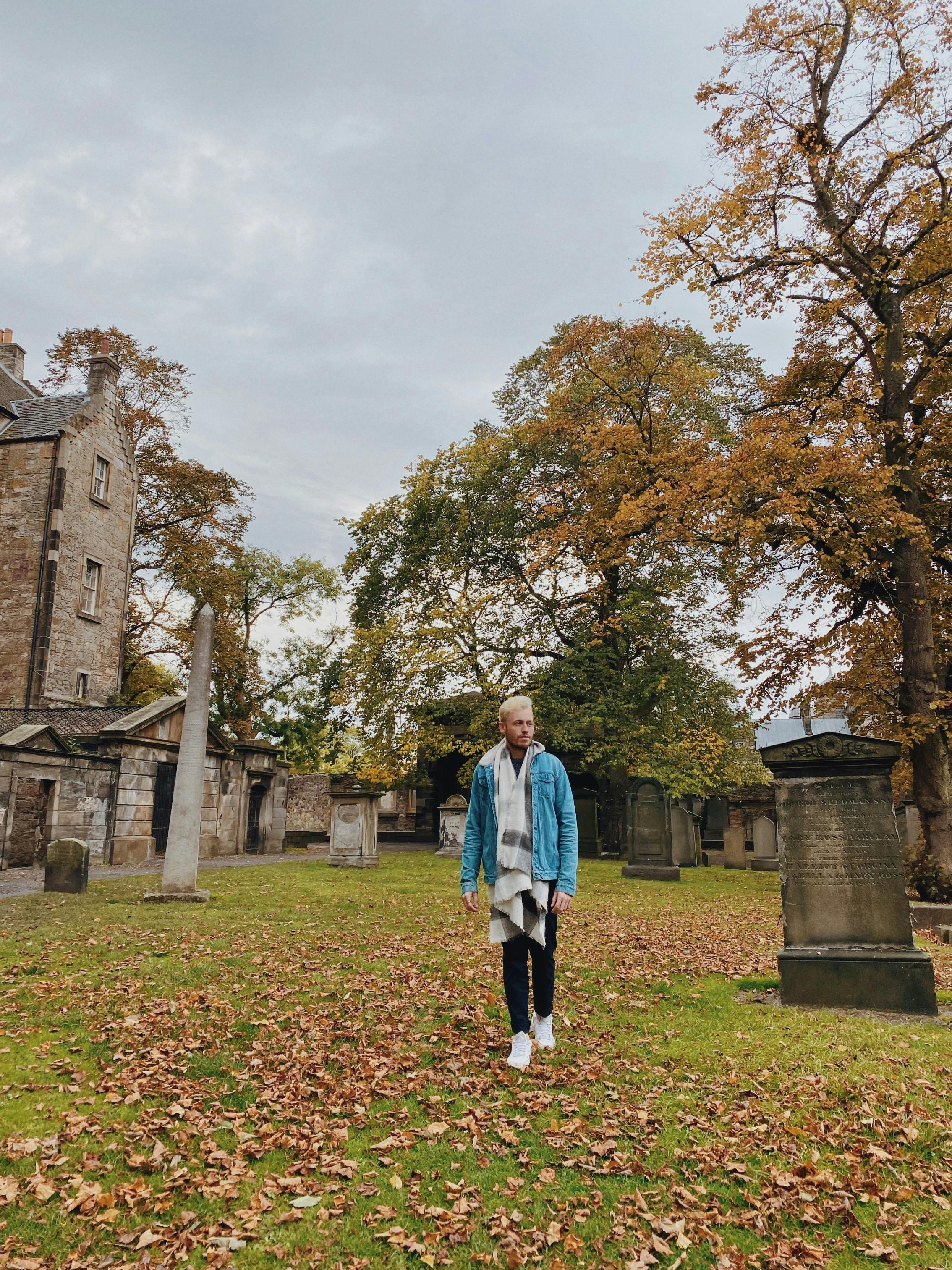 Young Man in Blue Denim Jacket Walking on Old Church Cemetery · Free