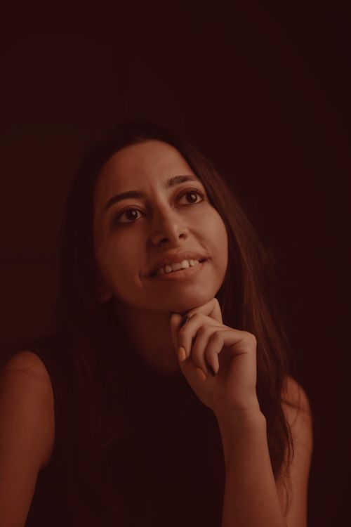 Free Portrait of a smiling woman in a serene and contemplative pose against a dark background. Stock Photo