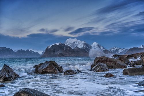 Free Breathtaking winter view of a rocky coastline with snow-capped mountains in Myrland, Nordland, Norway. Stock Photo