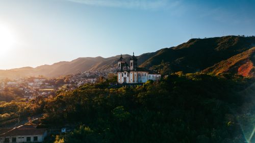 Free A stunning view of a historic church in Ouro Preto, Brazil, against a mountainous backdrop at sunset. Stock Photo