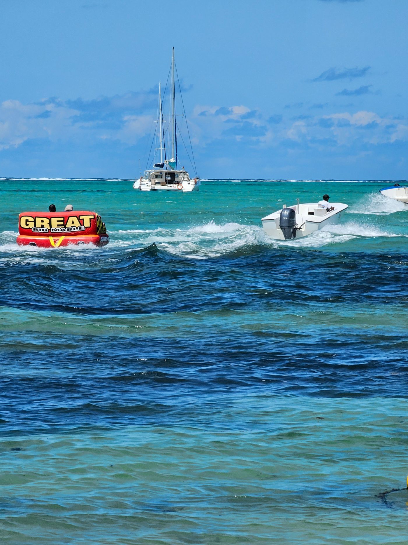 Motorboat towing an inflatable tube across tropical blue water