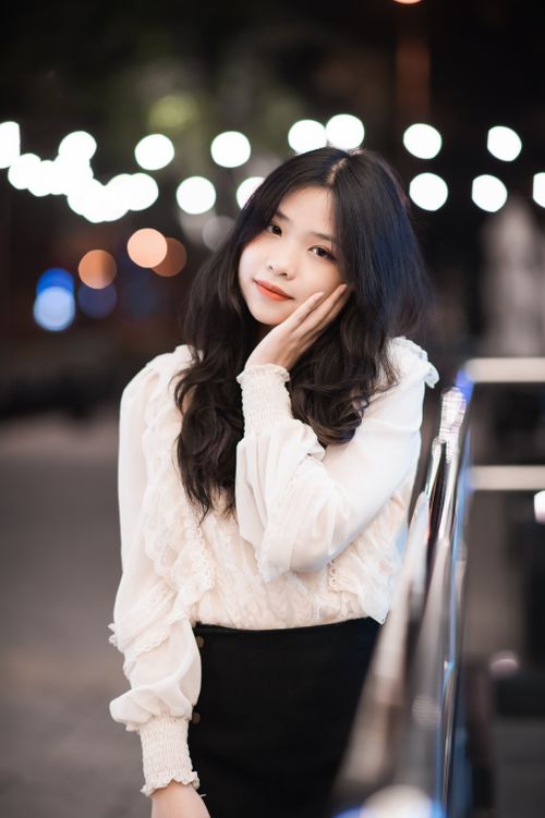 Free Stylish young woman in elegant attire poses confidently outdoors during the night. Stock Photo