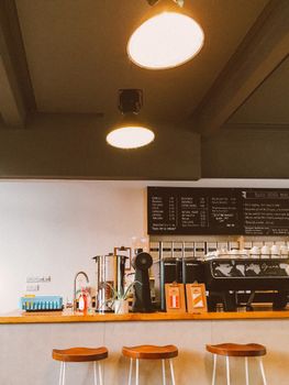 Warm and inviting coffee shop interior with stylish wooden stools and modern lighting.