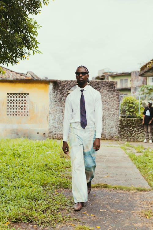 A Fashionable Man Walking on the Pavement