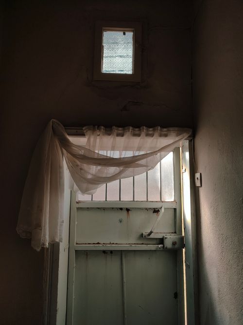 Free A rustic interior featuring a partially open wooden door with a sheer curtain and natural light. Stock Photo