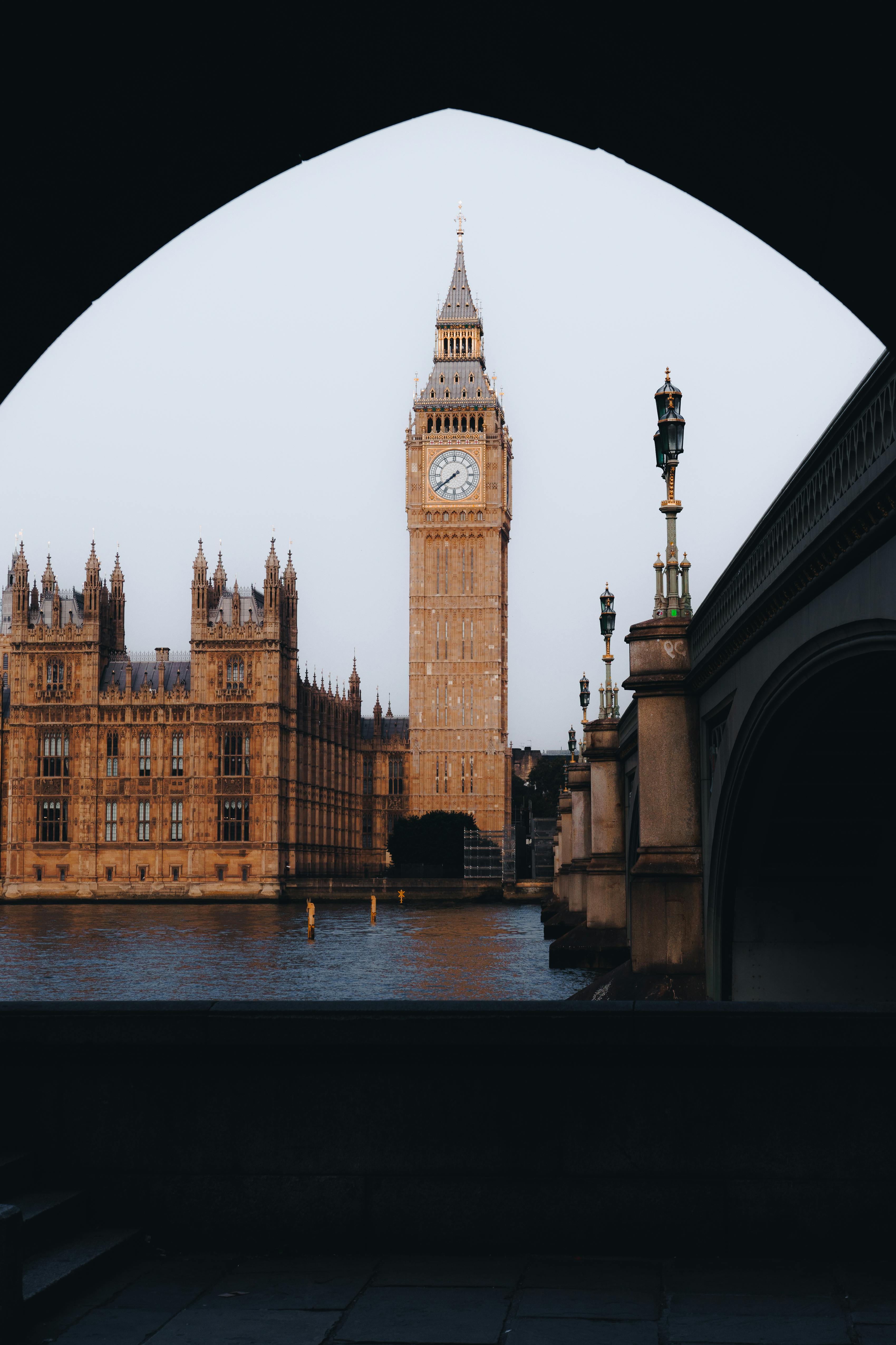 Iconic view of Big Ben and Houses of Parliament through a bridge arch in London.