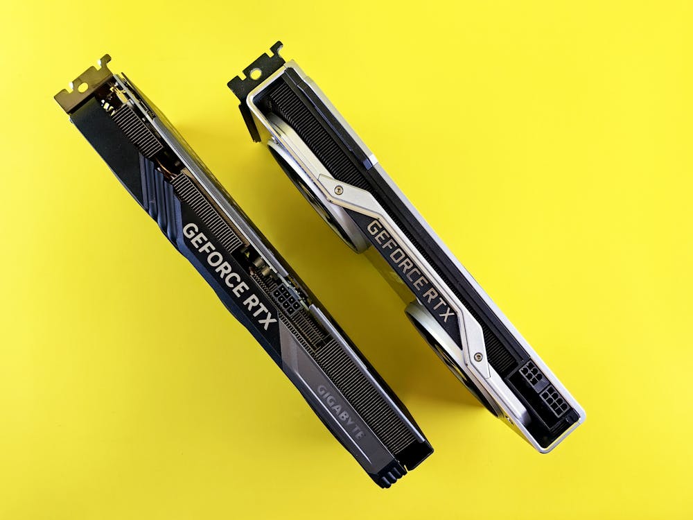 Free Top view of dual GeForce RTX graphics cards set against a bright yellow background, emphasizing modern technology. Stock Photo