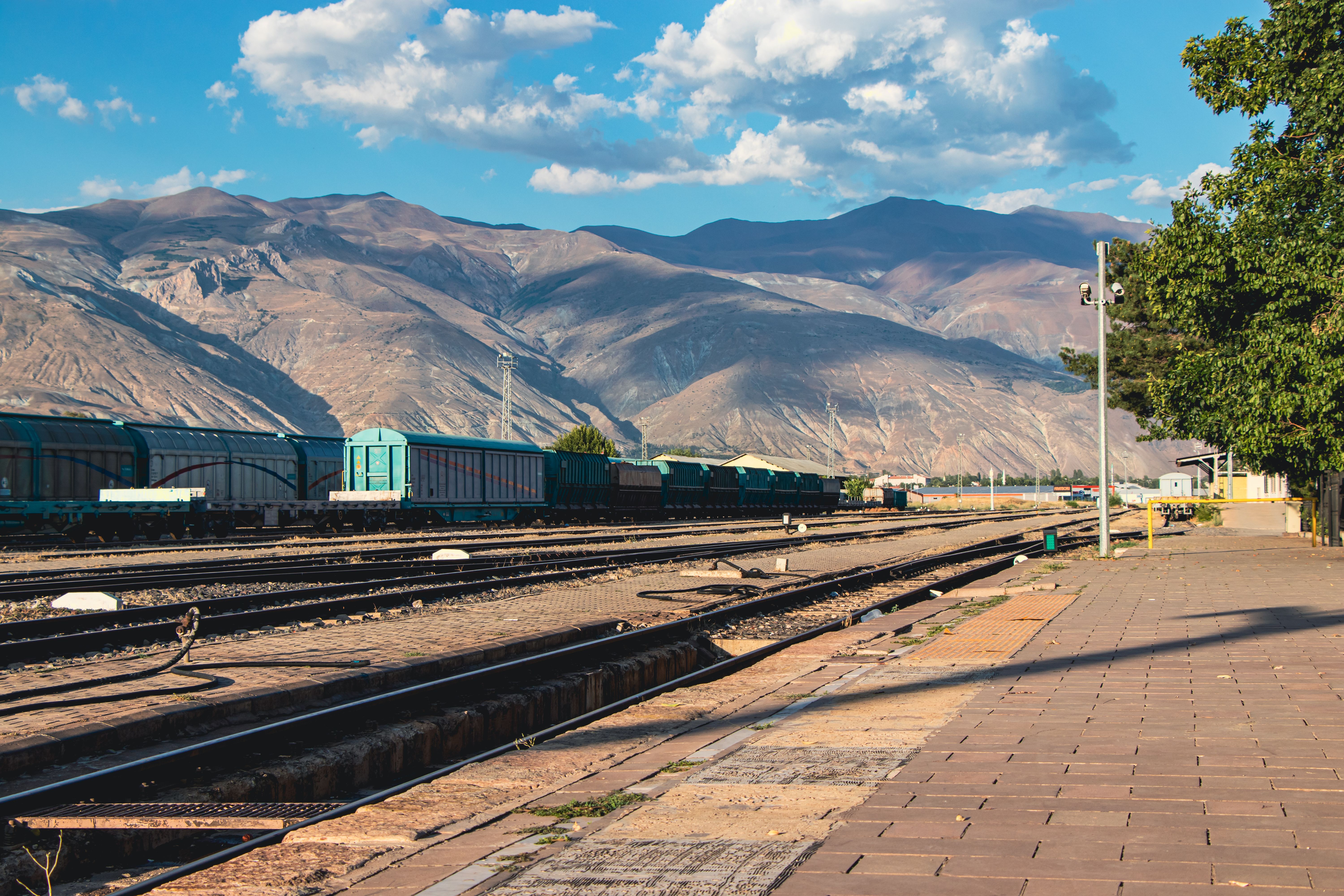 Railway station beside mountains under a clear sky, showcasing natural beauty and transportation.