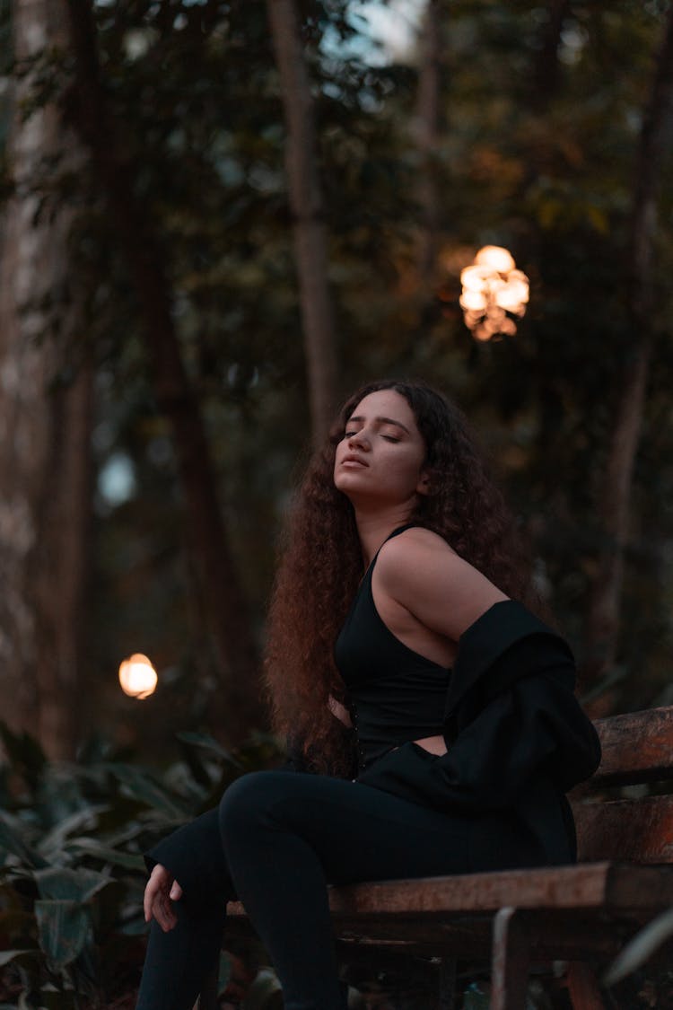 Woman In Black Halter Top Sitting On Bench In Park