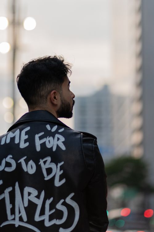 Free A man in a bold jacket with motivating text stands in an urban street setting. Stock Photo
