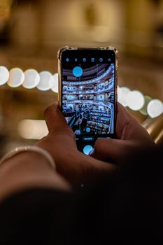 Close-up of hands holding smartphone, capturing ornate indoor architecture.
