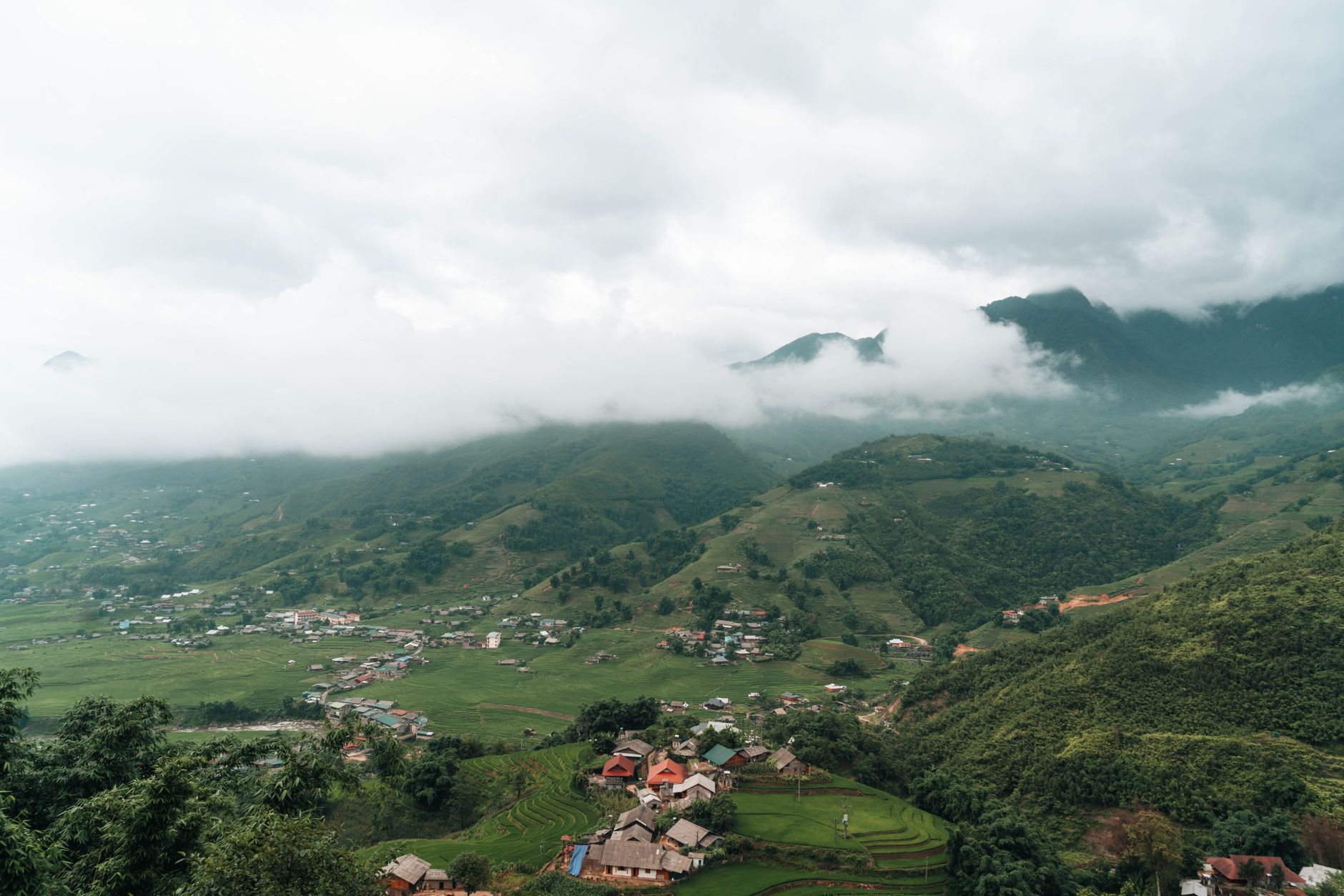 Scenic view of Lào Cai's lush mountains and valley enveloped in fog.