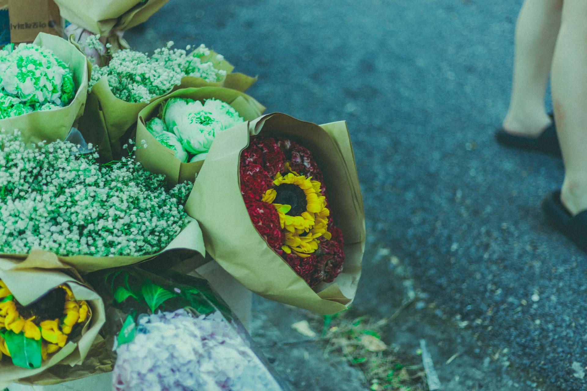 Vibrant flower bouquets wrapped in brown paper displayed on a city street.