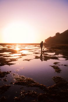 Man walking on wetland during a serene sunset, reflecting on calm waters.