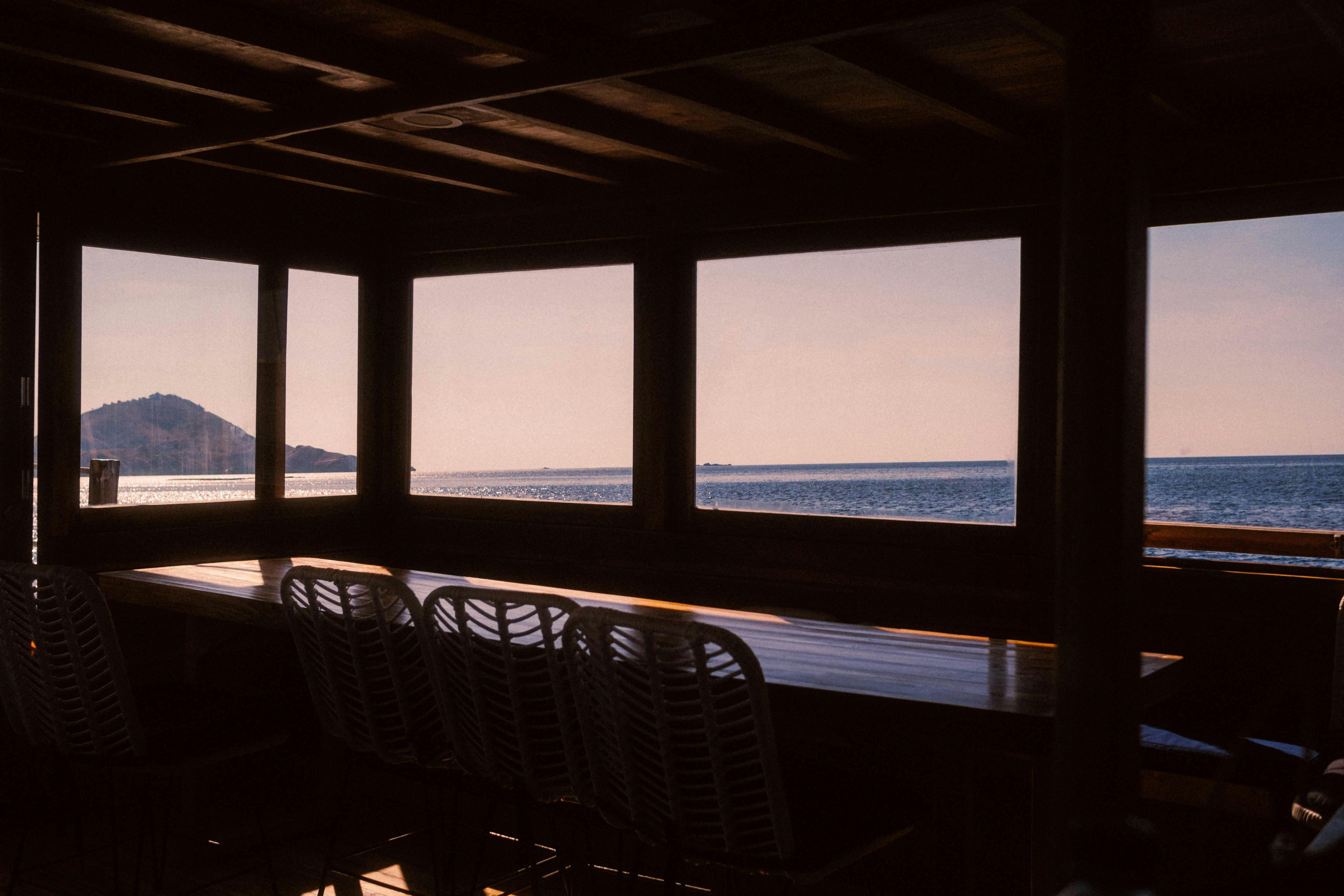 Spacious coastal restaurant with panoramic ocean views at sunset.