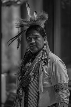 Black and white portrait of a person in traditional Indigenous attire, showcasing cultural heritage.