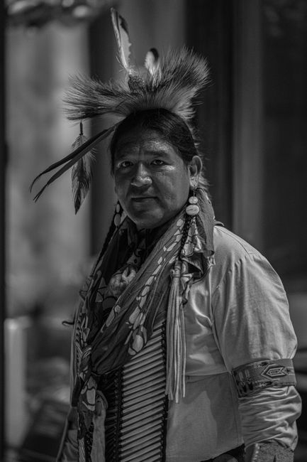 Black and white portrait of a person in traditional Indigenous attire, showcasing cultural heritage.