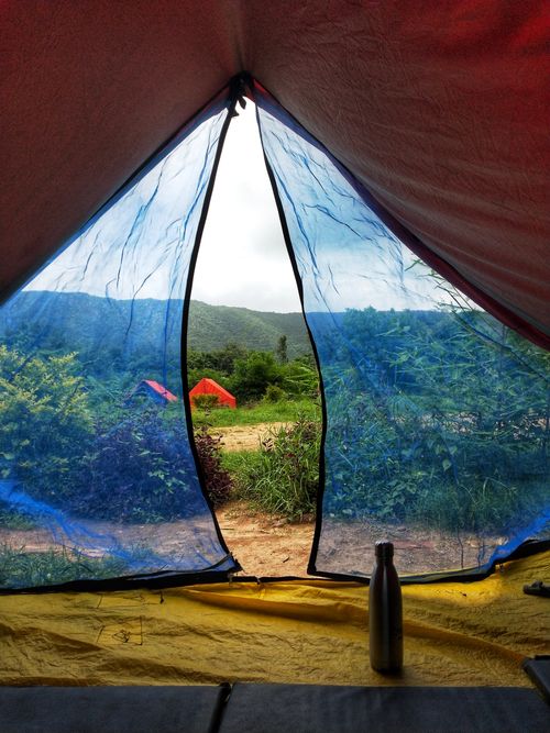 Free View from inside a tent in Vijayanagar, India, showcasing outdoor camping with colorful tents and lush scenery. Stock Photo