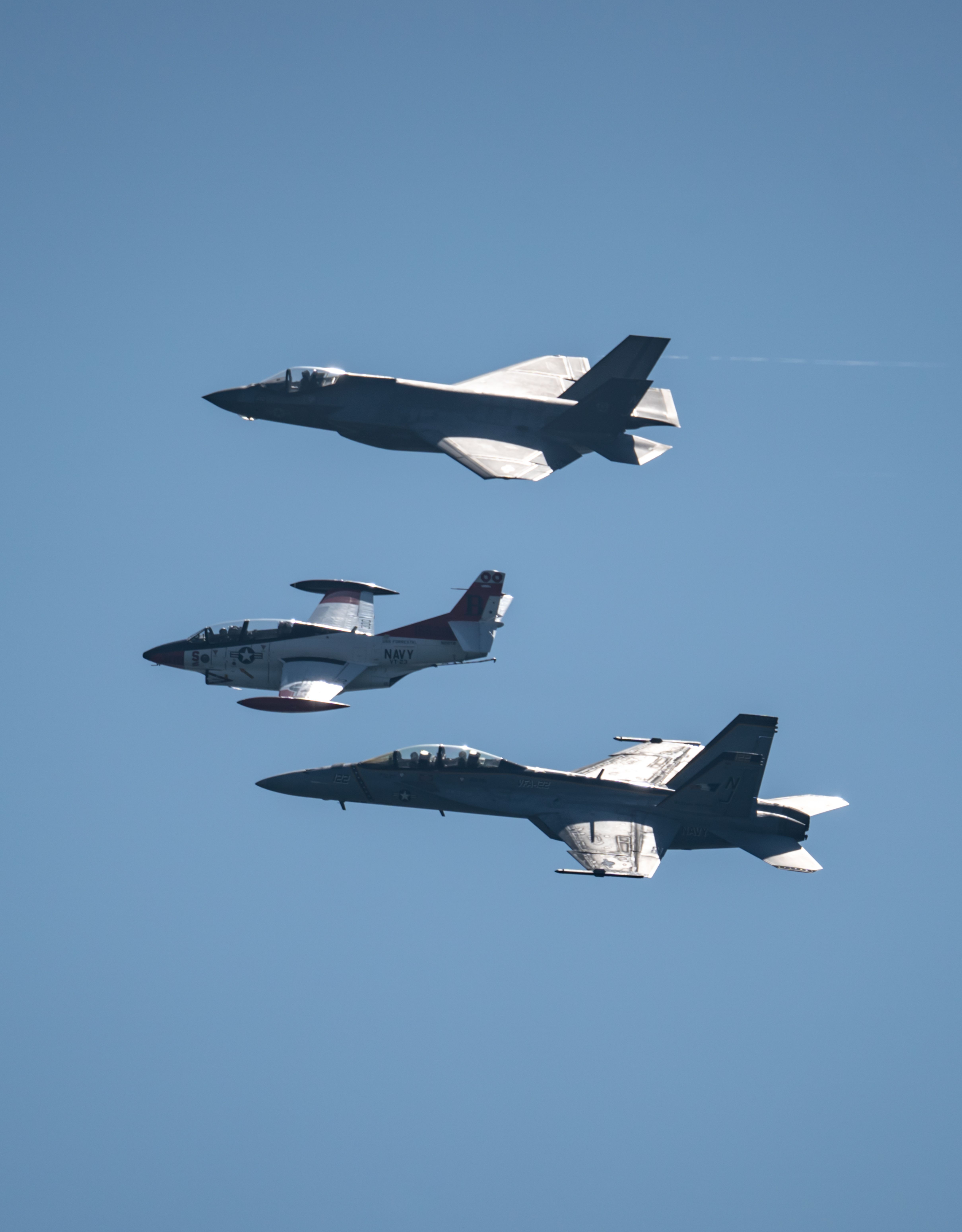 Three military jets in clear sky, showcasing power and precision in formation over Huntington Beach, CA.