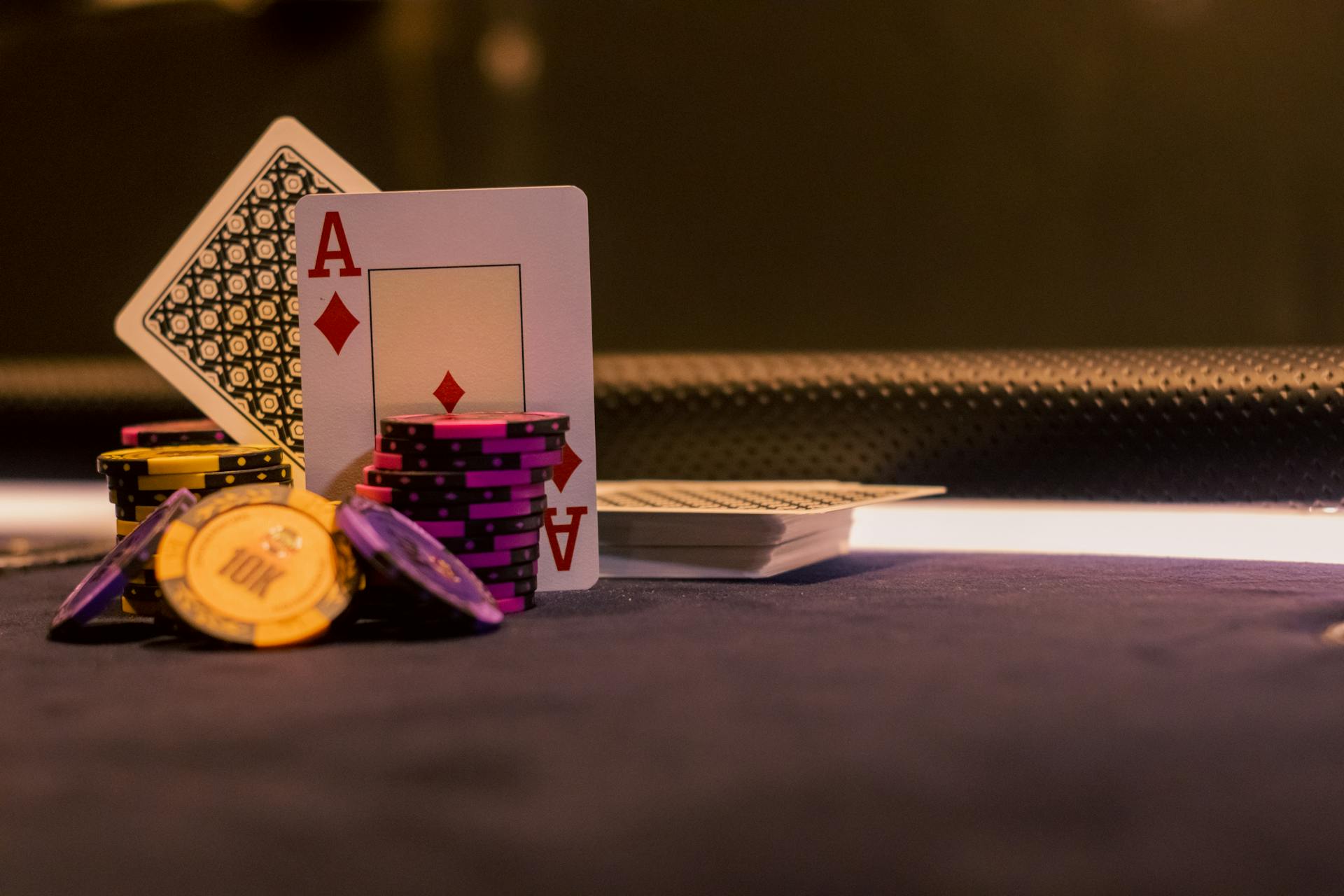 A close-up of poker chips and playing cards on a casino gaming table, highlighting Ace of Diamonds.