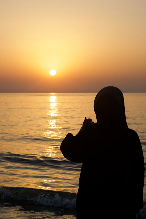 Silhouette of Woman by the Sea During Sunset