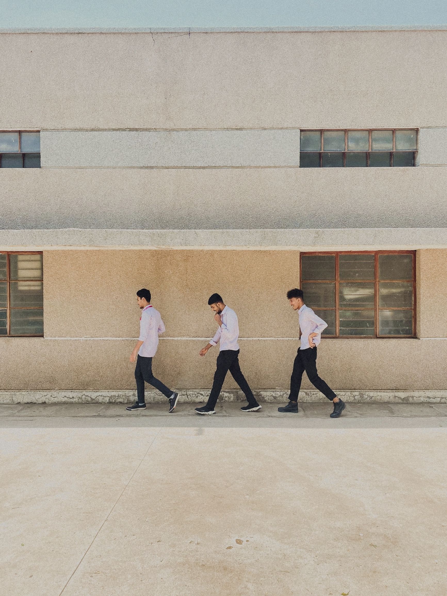 Men Walking in Line under Building · Free Stock Photo