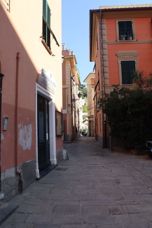 Free Explore the charm of a narrow alleyway in a sunlit European town, framed by colorful buildings. Stock Photo