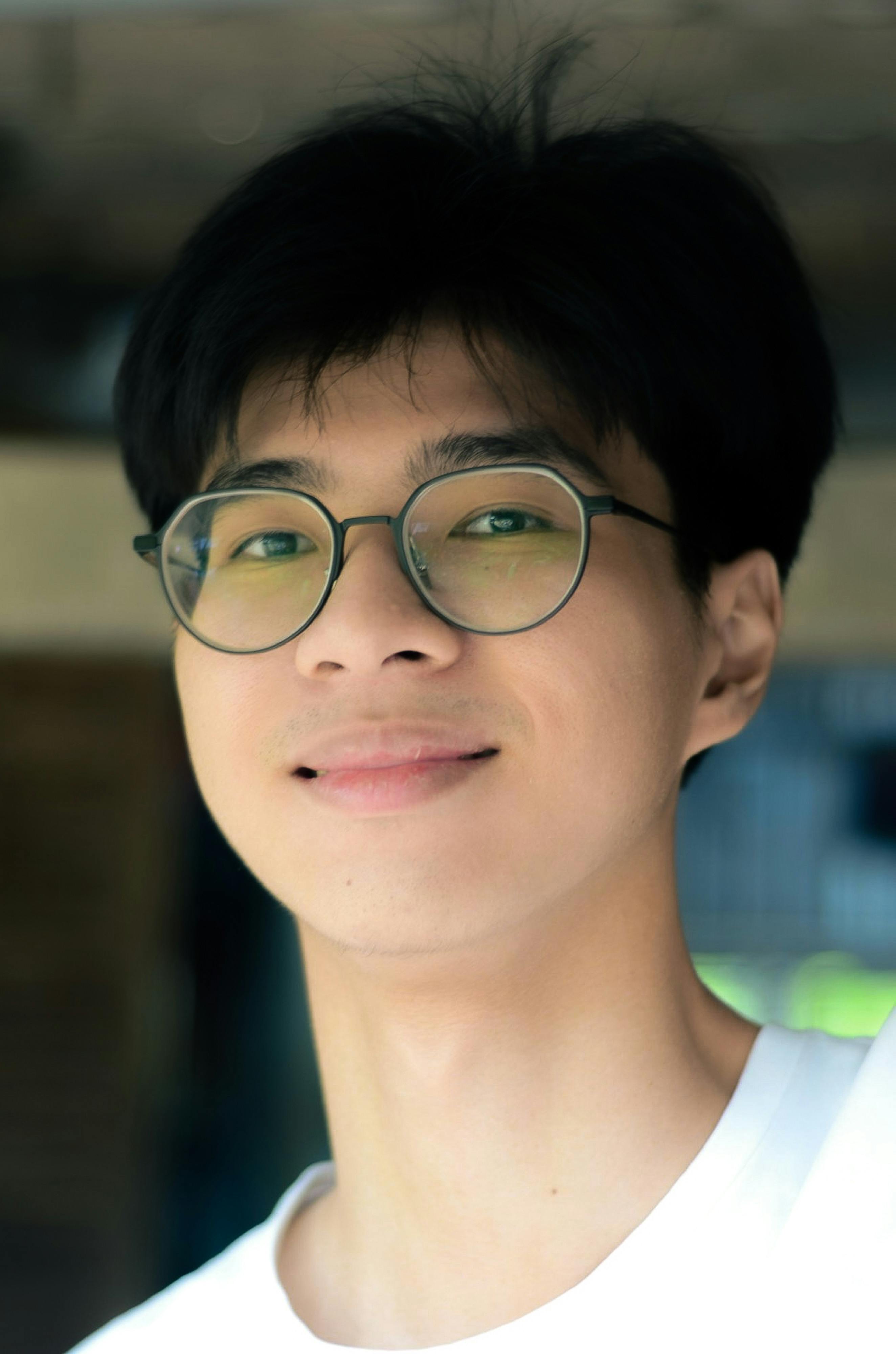 Portrait of a young man wearing eyeglasses, smiling warmly.