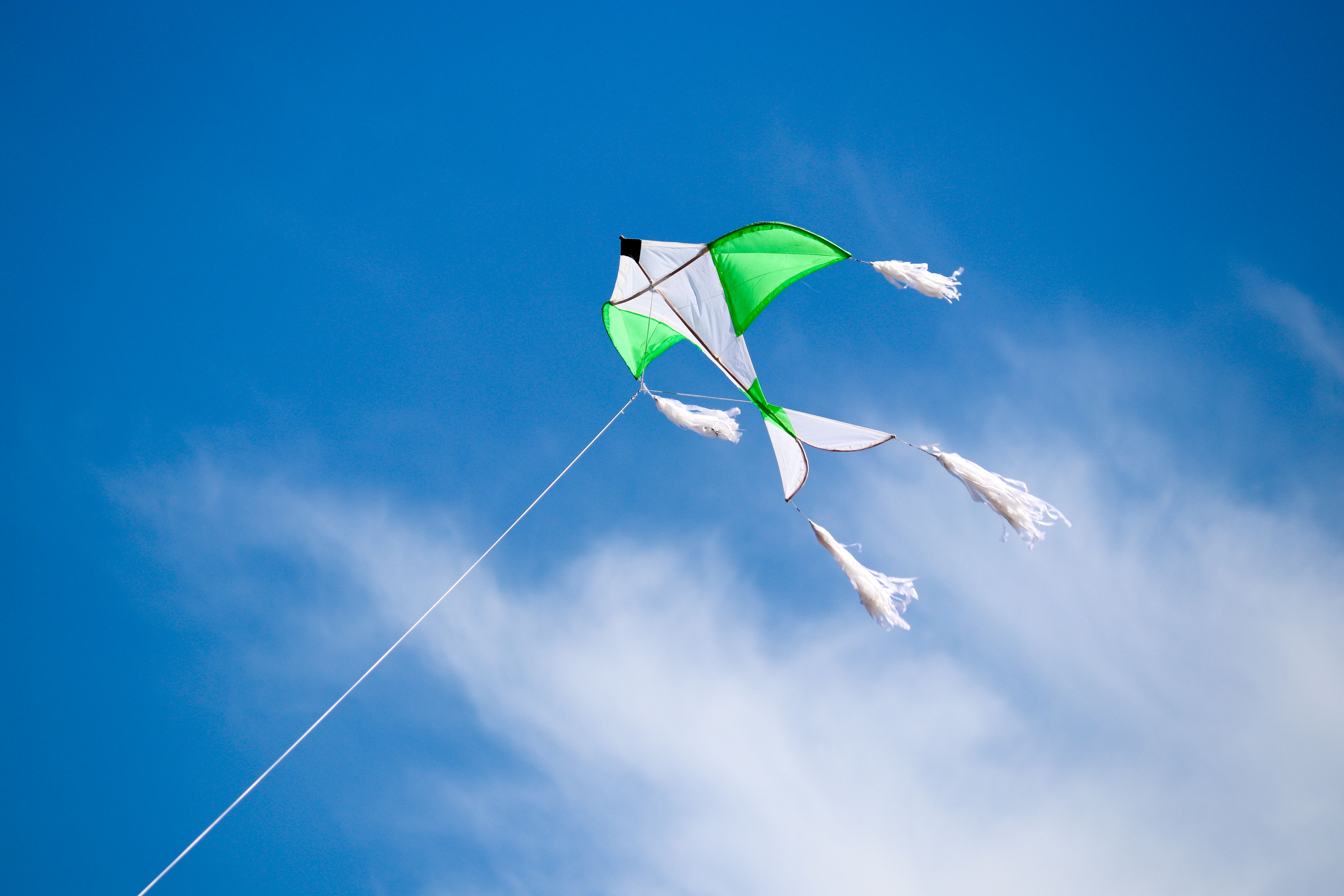 A vibrant green and white kite soaring against a clear blue sky over Cape Town.