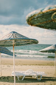Peaceful beach view with sun loungers and umbrellas under a bright sky.