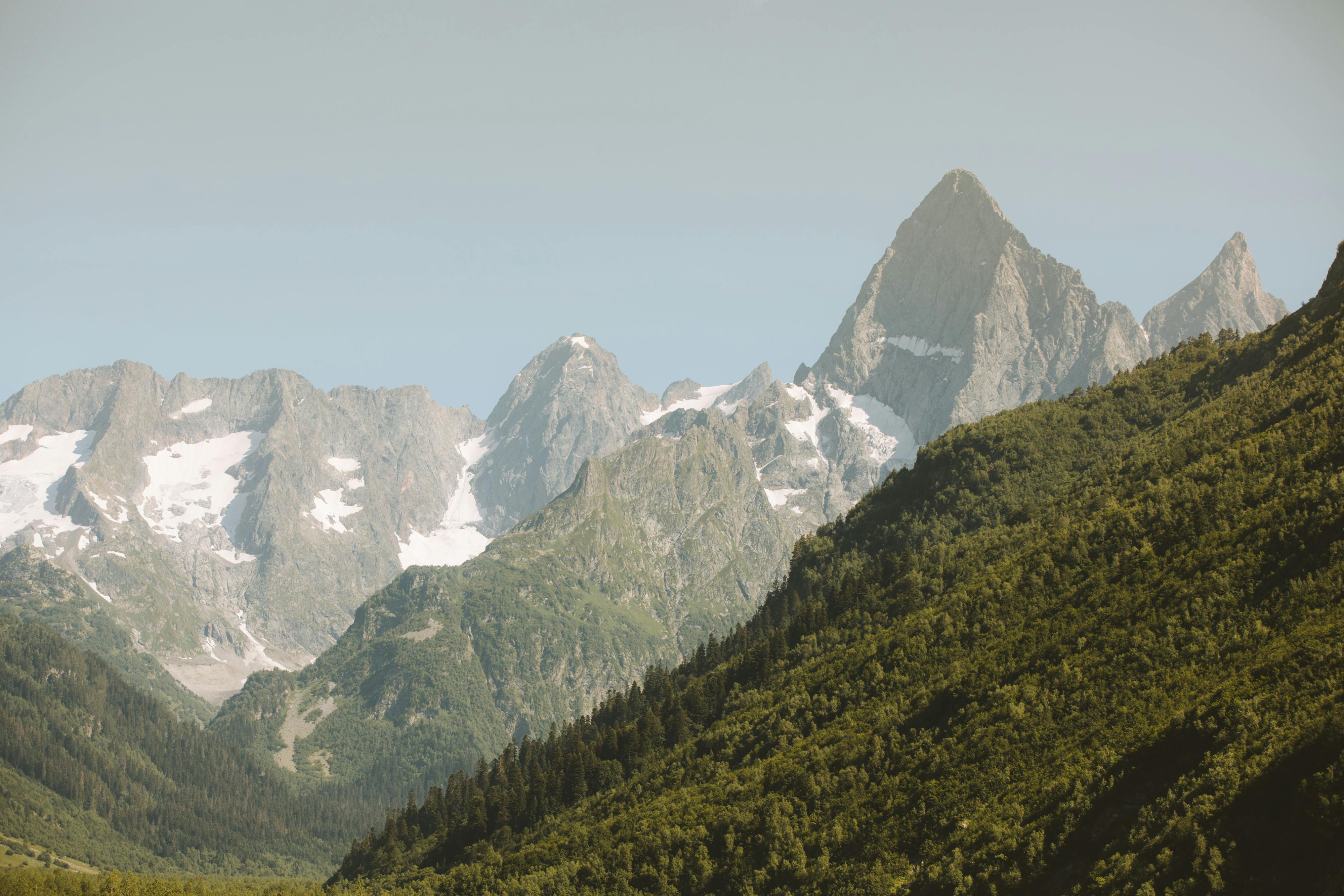 Prescription Goggle Inserts - Breathtaking view of towering mountain peaks with snow and lush green forests.