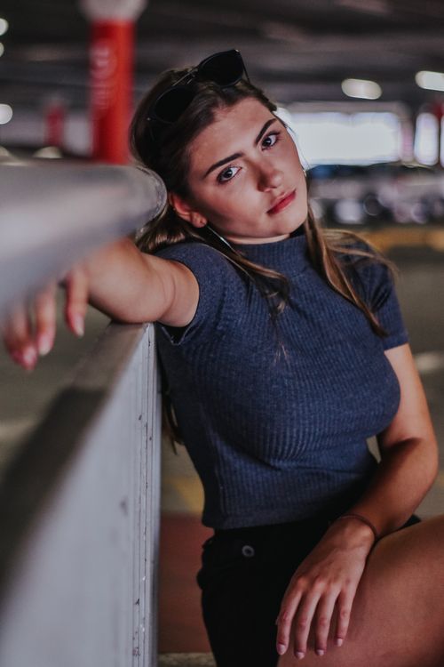 Free Portrait of a fashionable young woman posing stylishly in an urban parking lot. Stock Photo