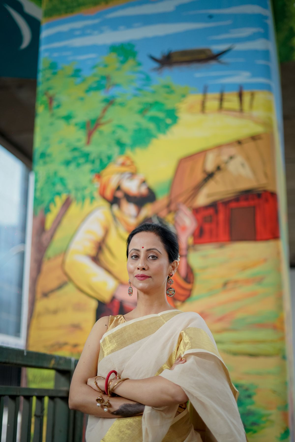 Woman in a traditional ivory sari before a painted folk mural