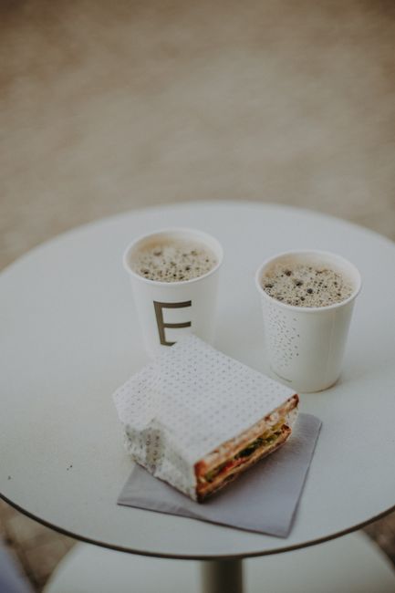 Coffee cups and a sandwich on a round table in Prague, creating a cozy brunch scene.