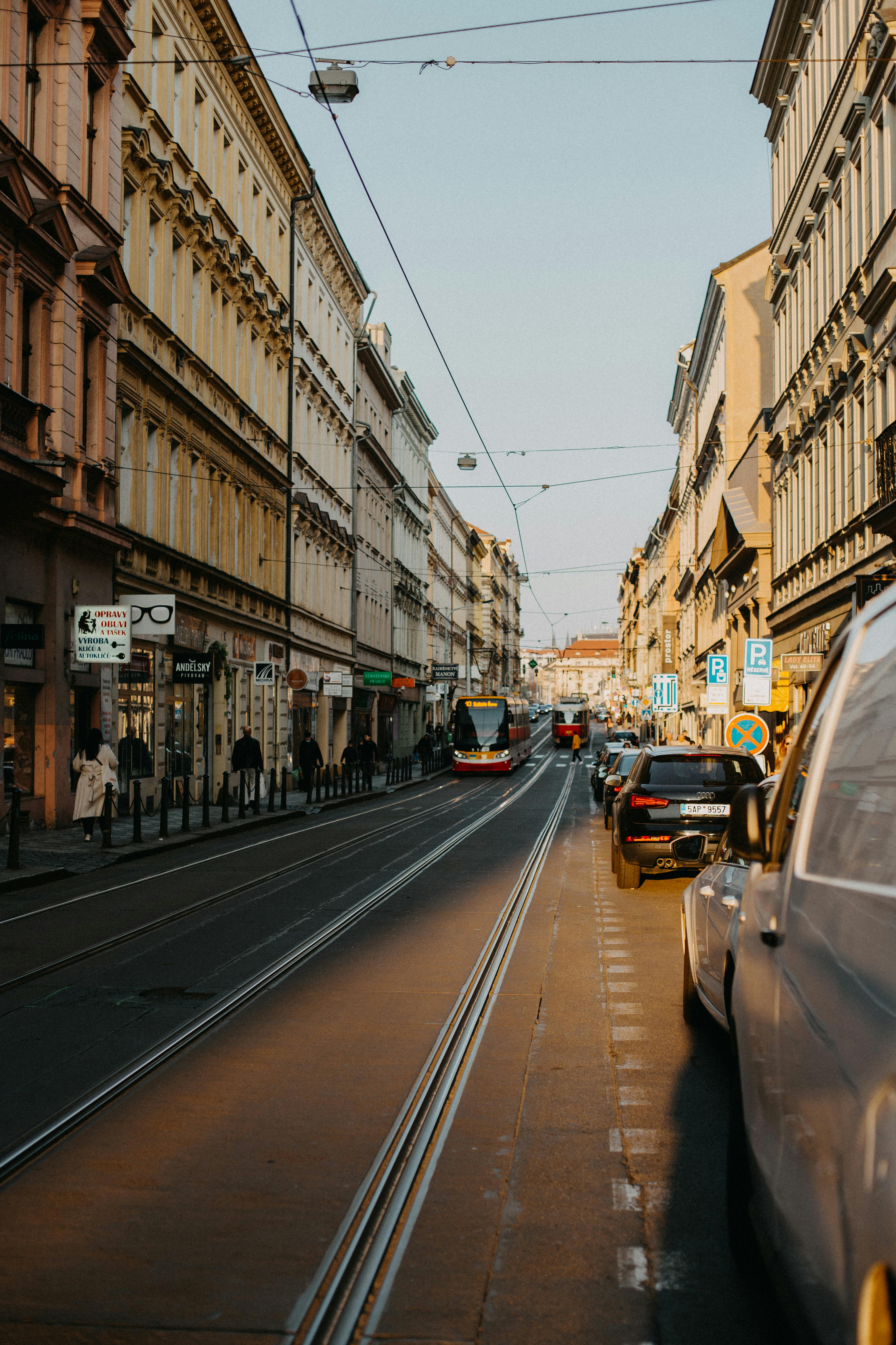 Discover the vibrant streets of Prague with trams and historical architecture at sunset.