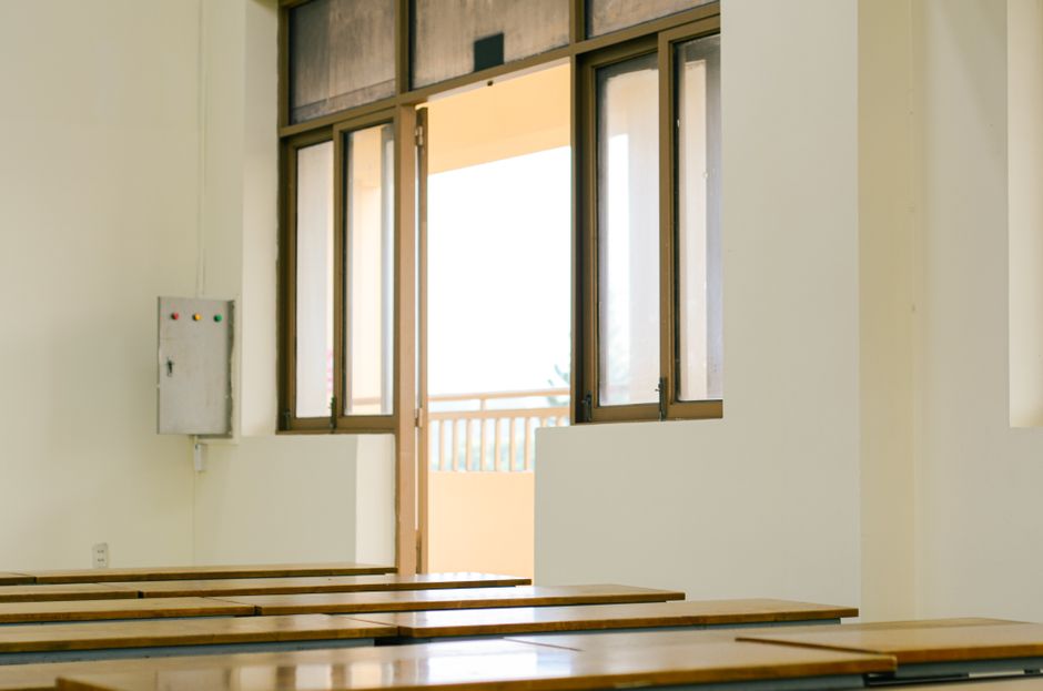 日差しが差し込む教室の内部、開いたドアと木製の机があり、教育テーマに最適です。
