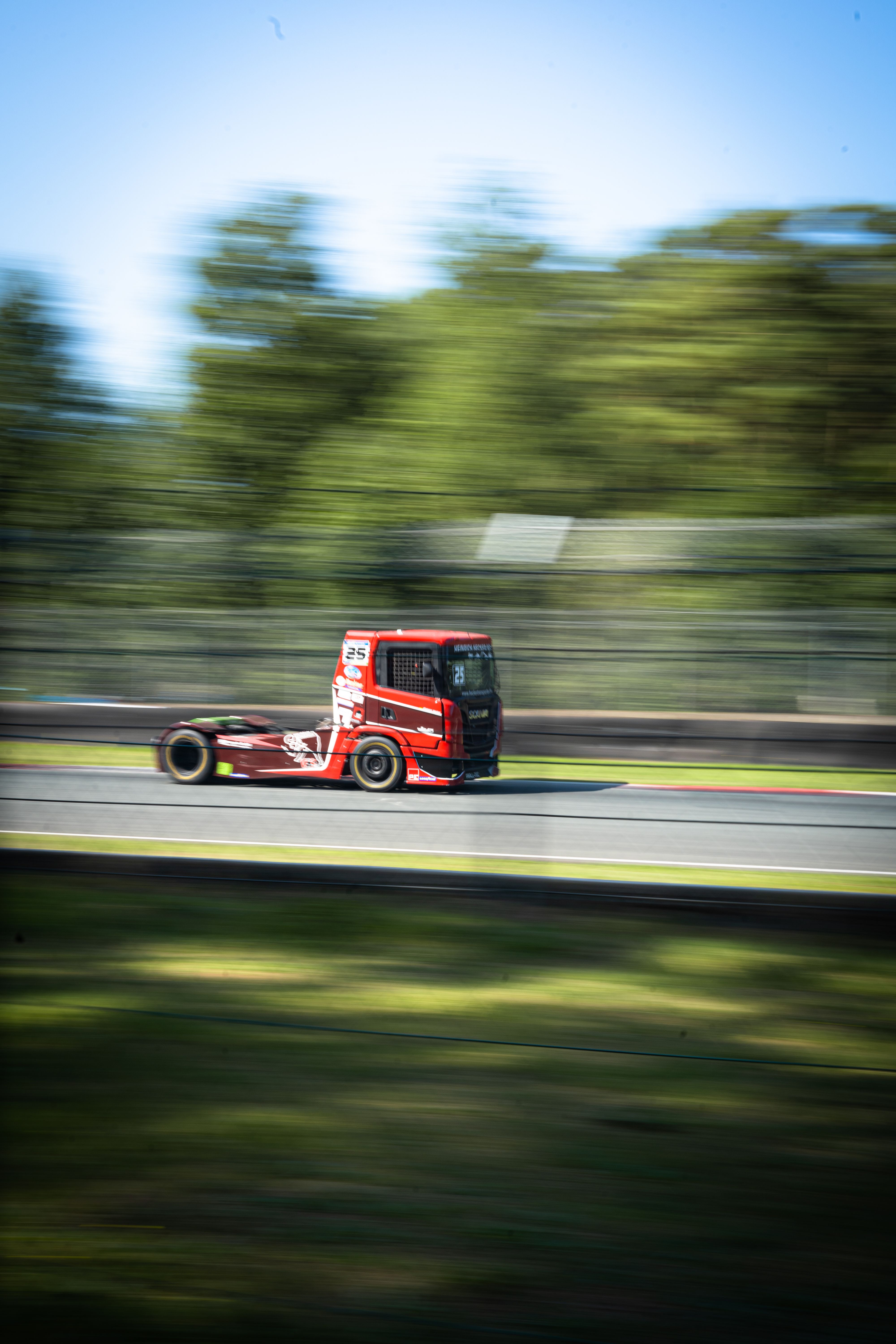 A motion-blurred red truck speeds down a racetrack, showcasing speed and power.