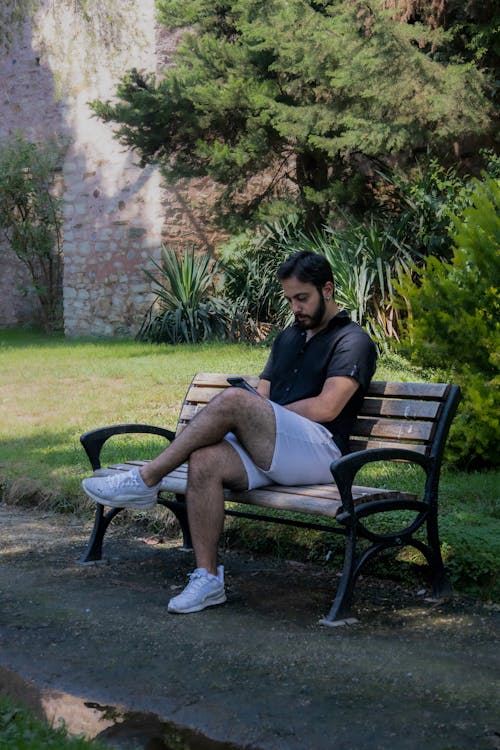 Man with a Smartphone Sitting on a Bench