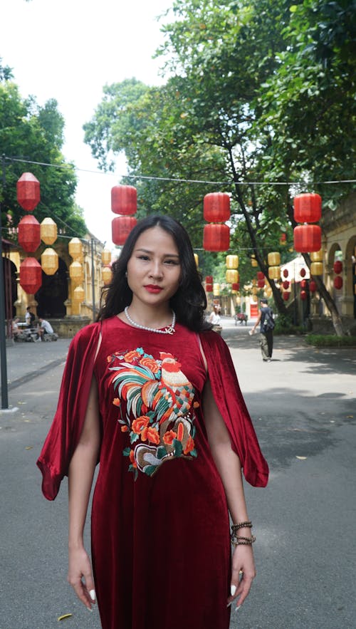 Young Woman in a Red Dress Posing in a Park Decorated with Lanterns