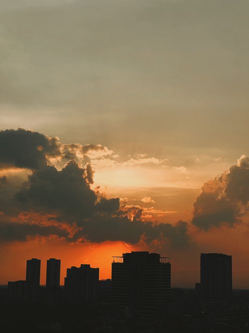 Free Silhouette of city buildings against a vibrant, dramatic sunset with striking cloud formations. Stock Photo
