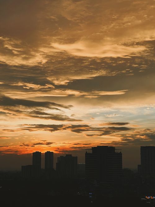 Free Silhouetted city skyline under a dramatic sunset sky, perfect for urban landscape themes. Stock Photo