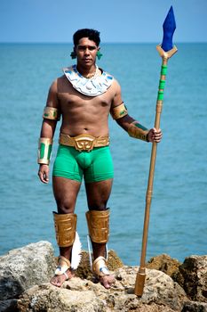 Man in tribal warrior costume holding spear by the sea shore. - Fotografer Sidoarjo