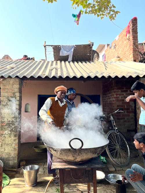 Free Man Preparing Food in a Large Wok Standing outside the House Stock Photo