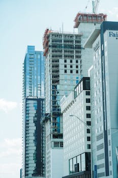 Urban skyline featuring a modern skyscraper under construction among established high-rise buildings.