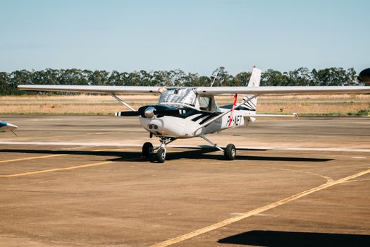 Parked light aircraft on an airport runway during a sunny day, ready for departure.