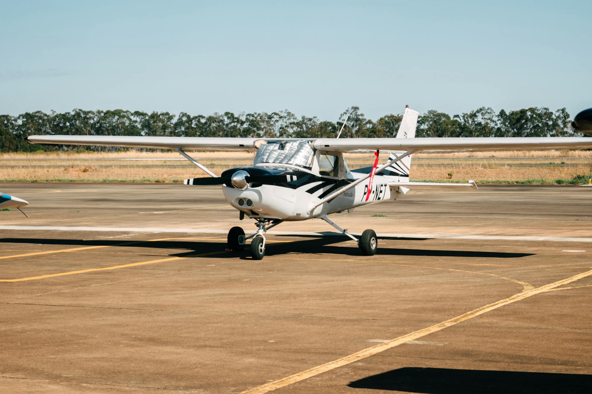 Parked light aircraft on an airport runway during a sunny day, ready for departure.
