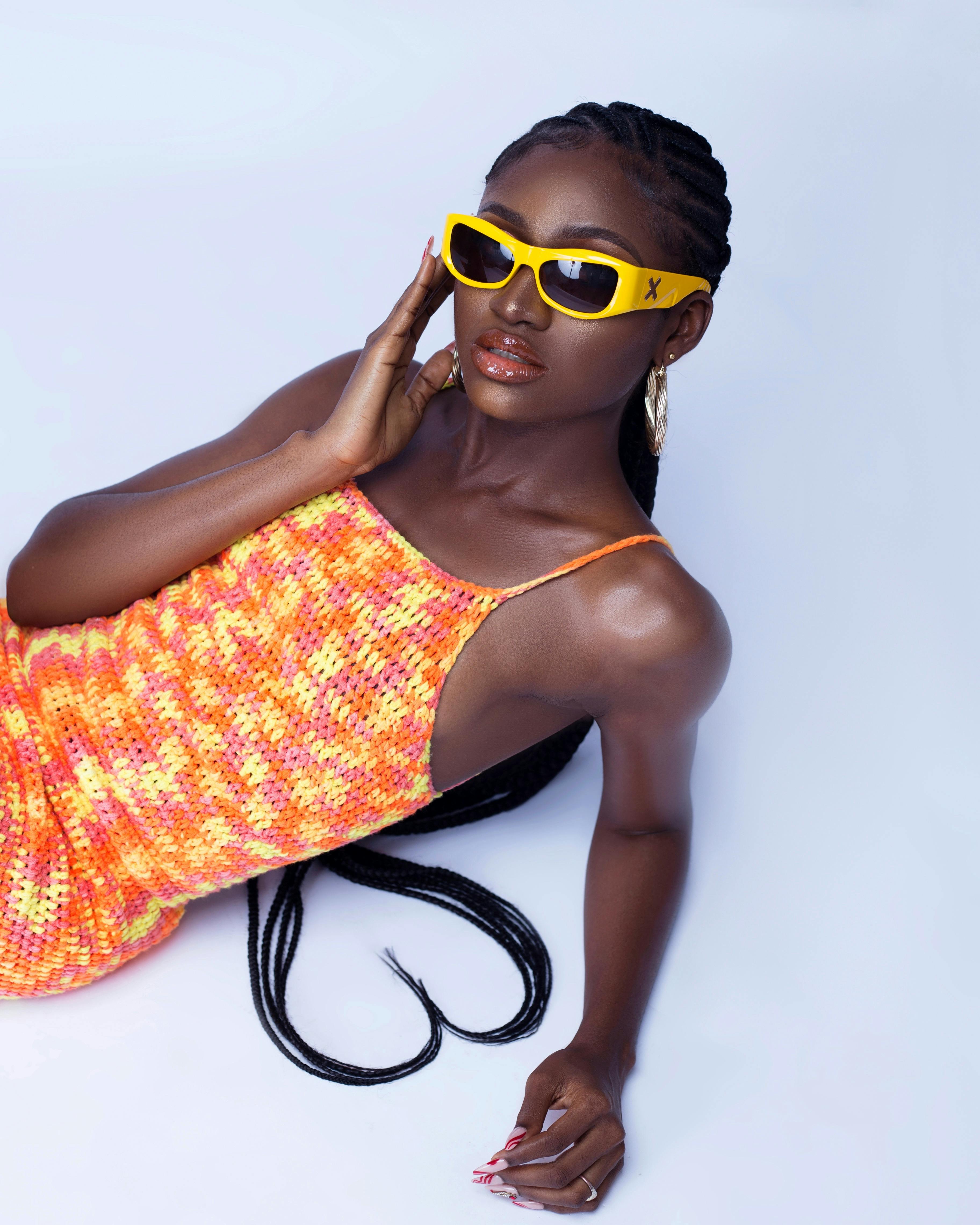 Dynamic studio shot of a fashionable woman posing in a colorful sundress and sunglasses.