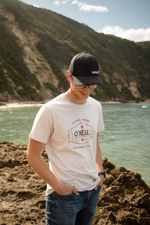 Smiling Man in Cap and T-shirt on Sea Shore