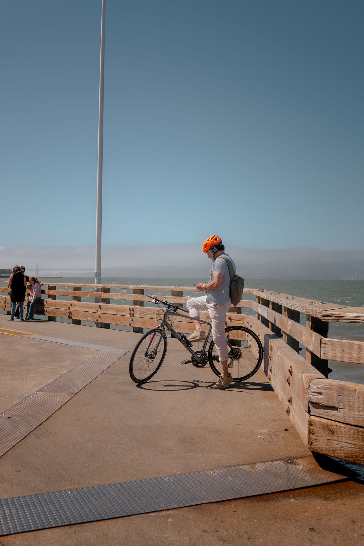 A cyclist wearing a helmet riding along a sunny coastal promenade by the sea