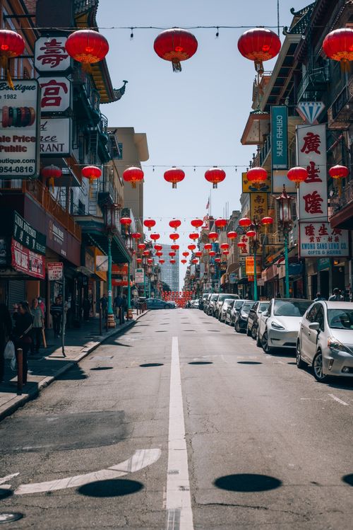 Free A lively urban street scene in Chinatown adorned with traditional red lanterns under a clear sky. Stock Photo